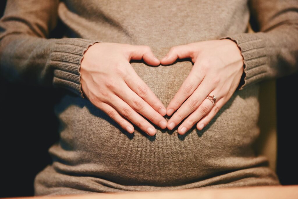 pregnant woman with hands making a heart over the growing belly. The belly changes visibly during pregnancy, but also the brain changes.