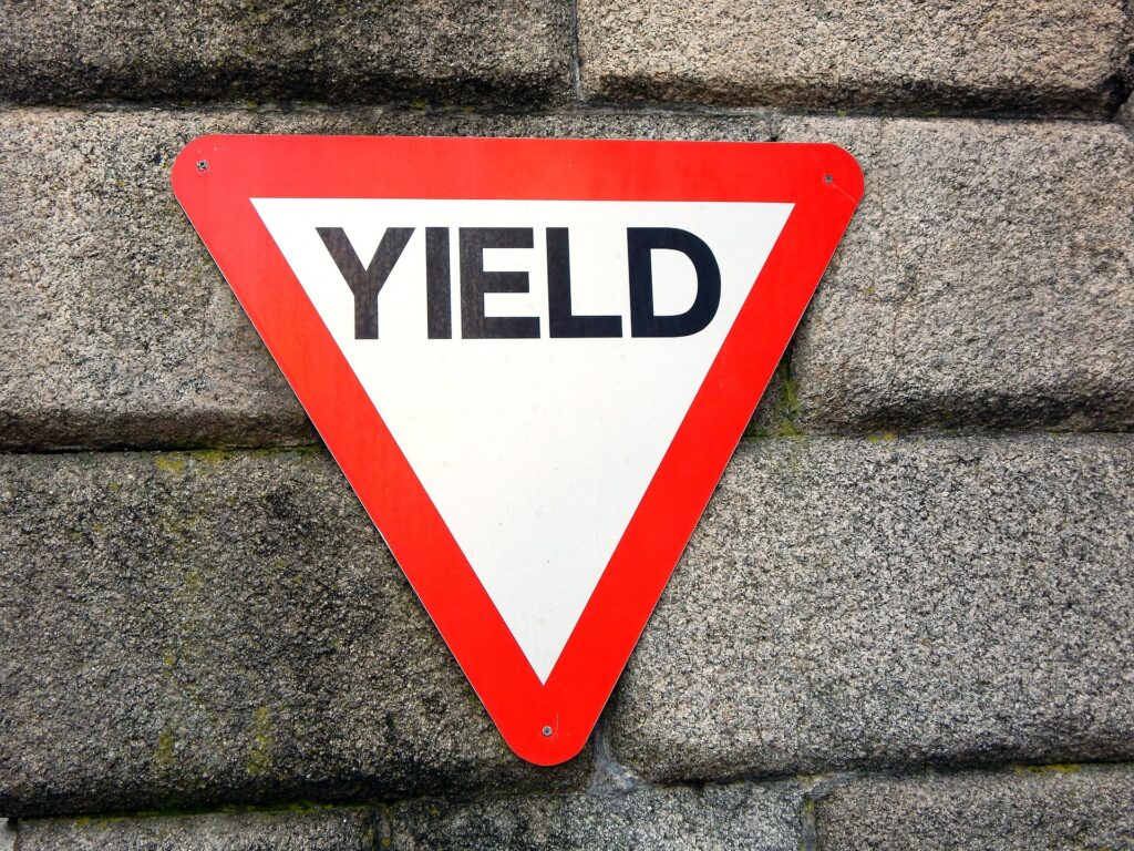 picture shows a street sign saying yield. We have learned to yield to the perception of others when it comes to our body rather than trusting ourselves paving the ground for maternal burnout.