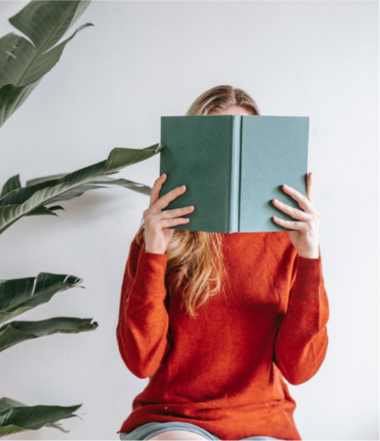 Women holding book in front of her face reading
