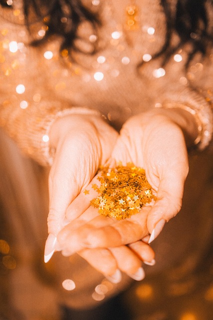 Hands of woman holding golden glitter stars, she's wearing a golden glitter dress too